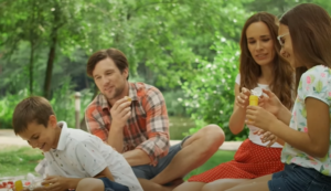 a group of people sitting on a blanket outside